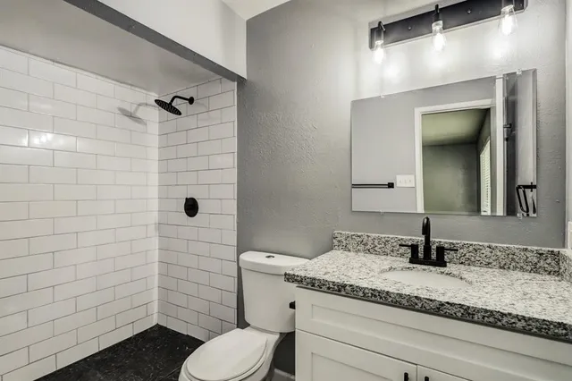 a bathroom with a granite countertop sink a toilet and mirror