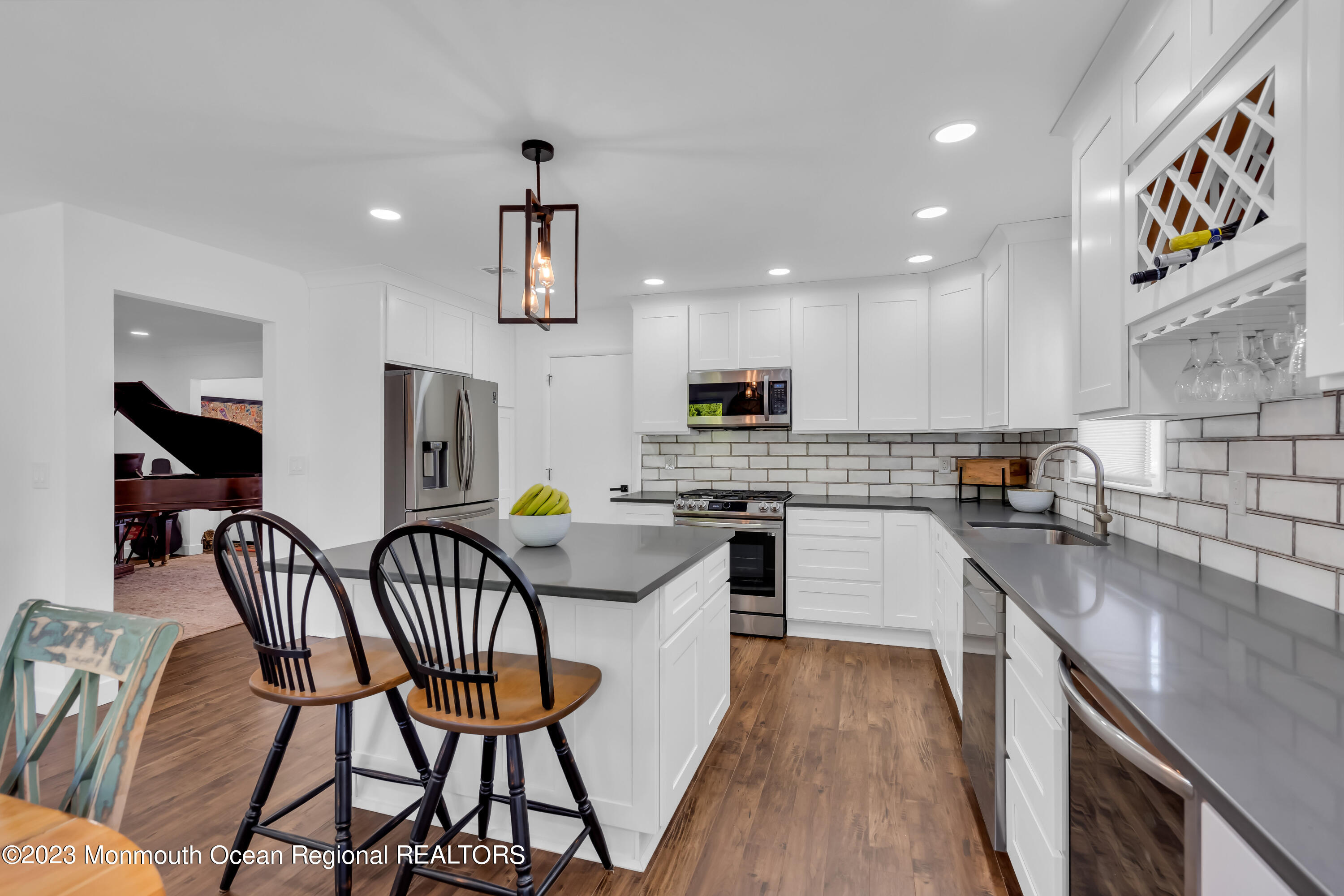 11 Garrett Road Toms River, NJ 08757 - Photo 32 of 61 a kitchen with stainless steel appliances kitchen island granite countertop a refrigerator a stove a sink dishwasher with a dining table and chairs with wooden floor