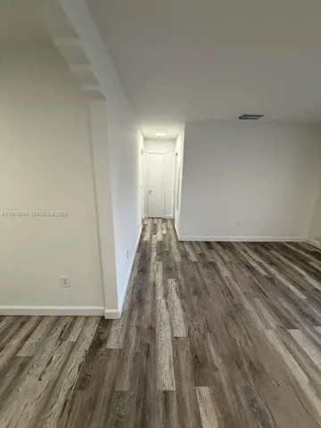 a view of empty room with window and wooden floor