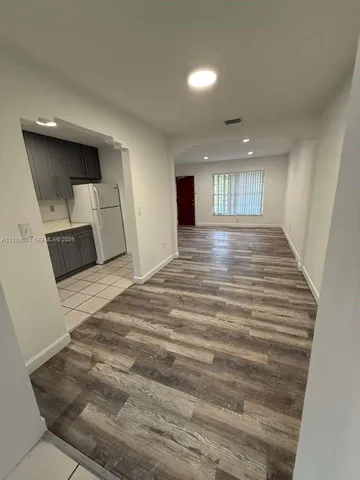 a view of empty room with kitchen and window