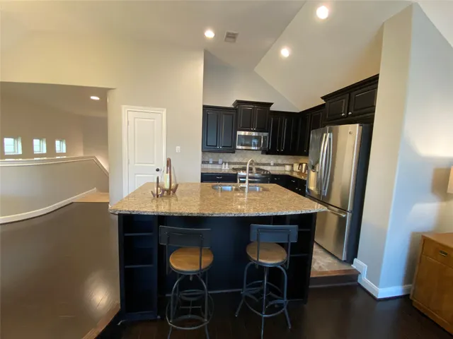 a kitchen with stainless steel appliances granite countertop a sink refrigerator and cabinets