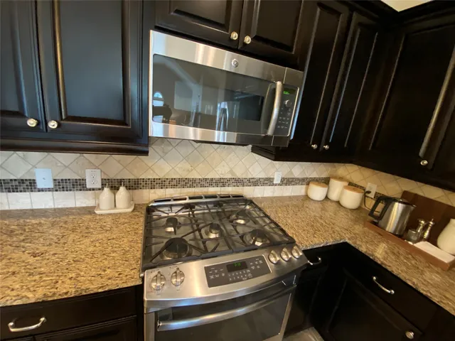 a kitchen with granite countertop a stove and a microwave