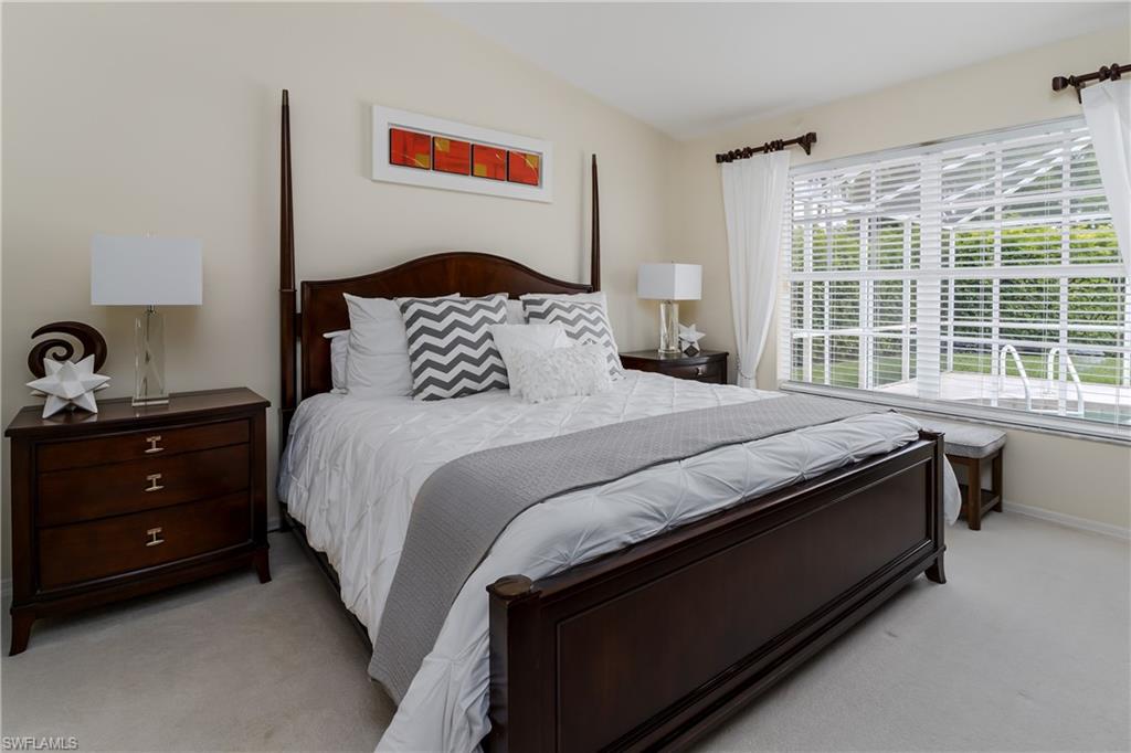 6658 Castlelawn Place, Unit 9 Naples, FL 34113 - Photo 16 of 38 Living area featuring wood-finish flooring, vaulted ceilings, and direct access to the outdoor screened patio through sliding glass doors