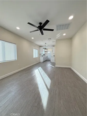 an empty room with wooden floor ceiling fan and windows
