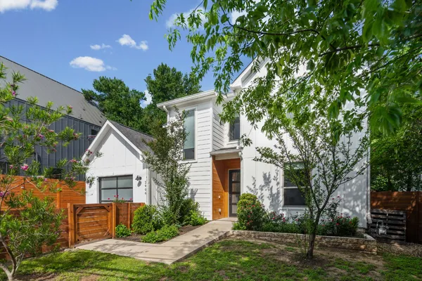 a front view of a house with a garden and tree