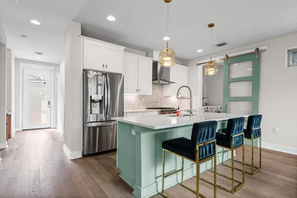 a kitchen with kitchen island a sink stove and refrigerator with wooden floor