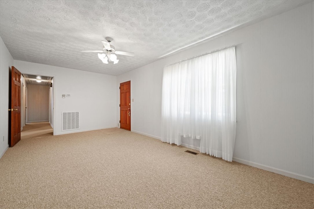 304 Shaw Road Honea Path, SC 29654 - Photo 16 of 39 This bright living area features soft carpeting, a ceiling fan, and ample natural light through expansive windows.