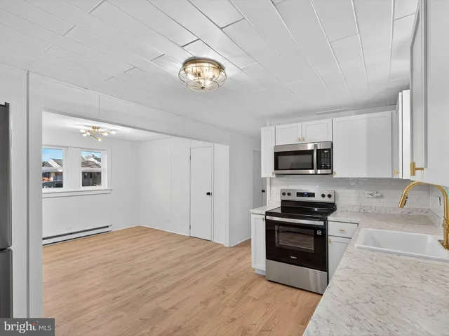 a kitchen with stainless steel appliances a stove top oven a sink a counter space and cabinets