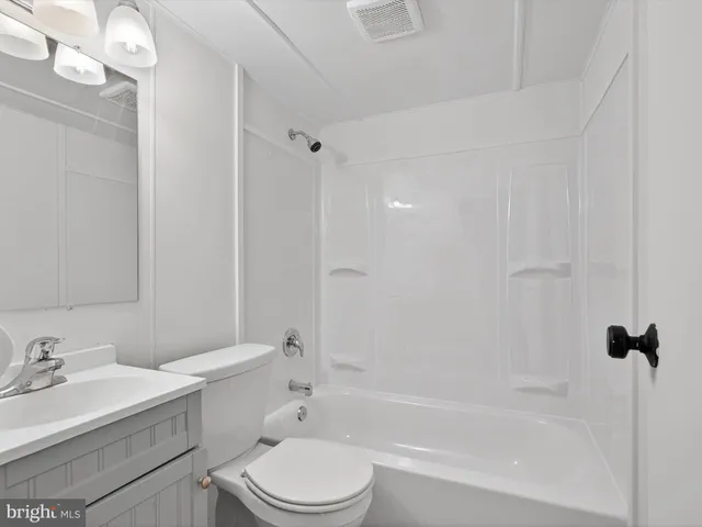 a bathroom with a bathtub shower sink vanity mirror and toilet