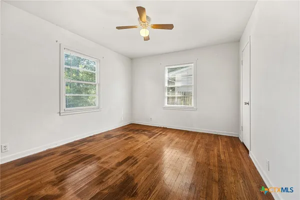 a view of an empty room with window and wooden floor