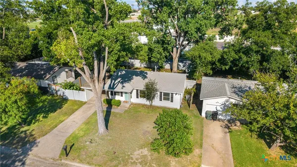 an aerial view of a house with swimming pool and large trees