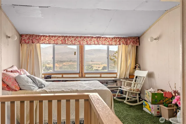 a bedroom with a bed and large windows