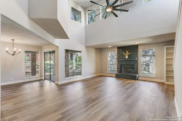 a view of an empty room with wooden floor and a ceiling fan