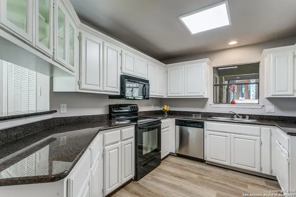 a kitchen with stainless steel appliances granite countertop white cabinets sink and stove