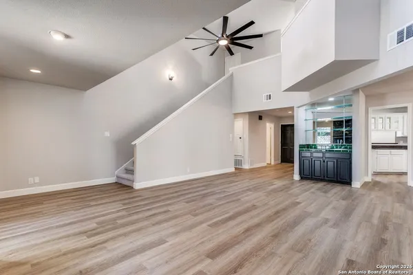 a view of empty room with wooden floor and kitchen view