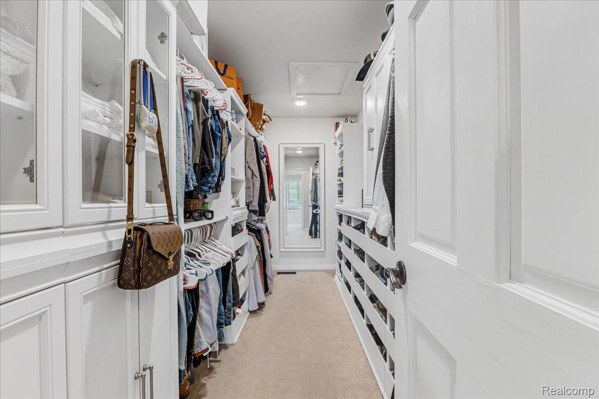 69075 Brookhill Drive Romeo, MI 48065 - Photo 10 of 28 Custom closet system featuring extensive built-in cabinetry, open shelving, glass-fronted cabinets, shoe racks, and carpet flooring