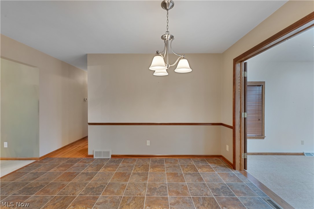 6599 Struthers Road Youngstown, OH 44514 - Photo 10 of 29 Spare room with stone finish flooring and hanging lights