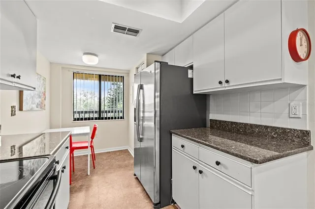 a kitchen with granite countertop a refrigerator and a stove top oven