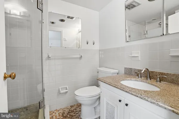 a bathroom with a granite countertop sink toilet and shower
