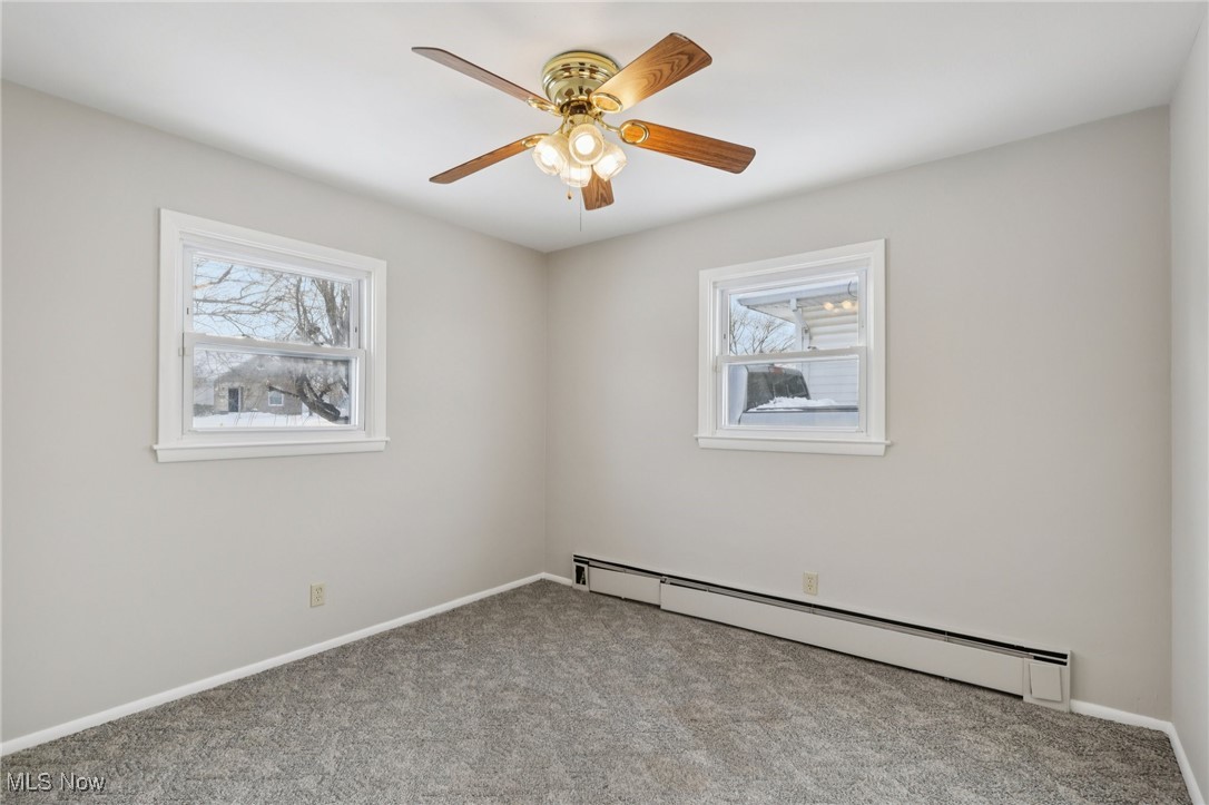 611 Wilson Street Struthers, OH 44471 - Photo 30 of 44 Empty room featuring baseboard heating, carpet, healthy amount of natural light, and a ceiling fan
