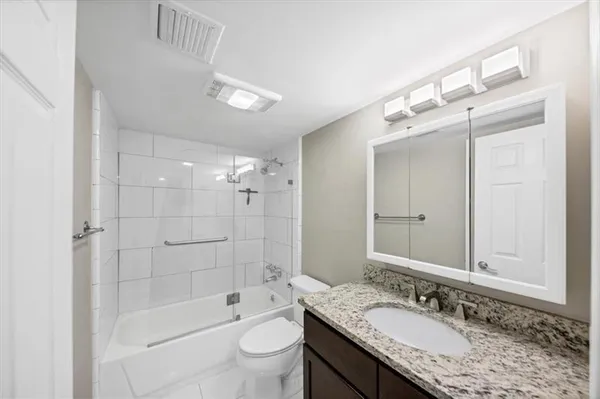 a bathroom with a granite countertop sink a toilet a mirror and shower