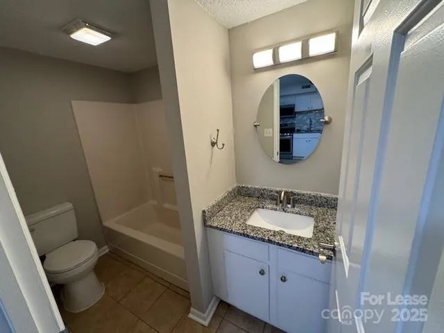 a bathroom with a granite countertop sink a mirror a toilet and a shower