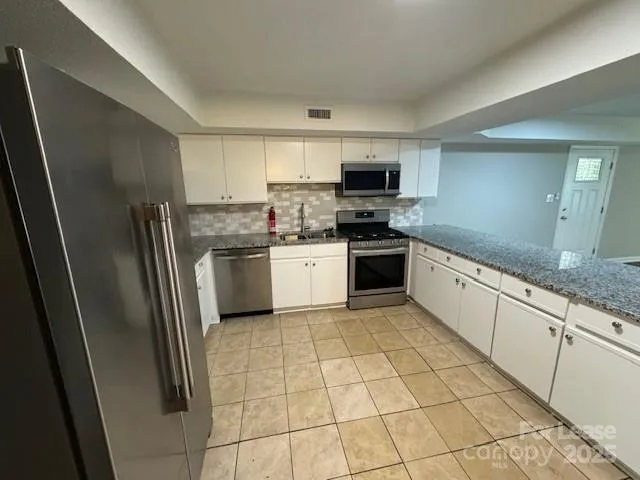 a kitchen with stainless steel appliances granite countertop a refrigerator and a stove top oven