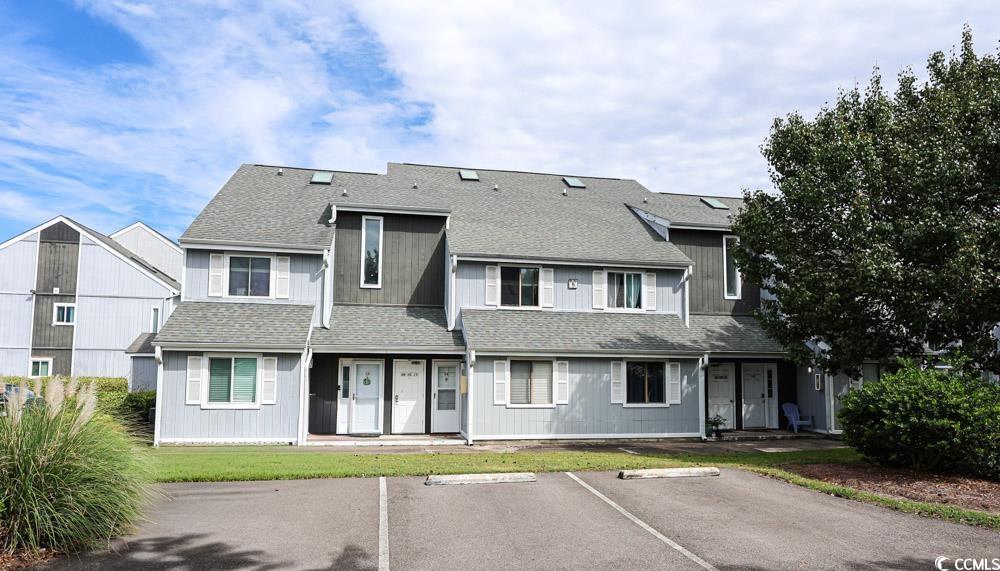 View of front of property featuring roof with shingles and uncovered parking