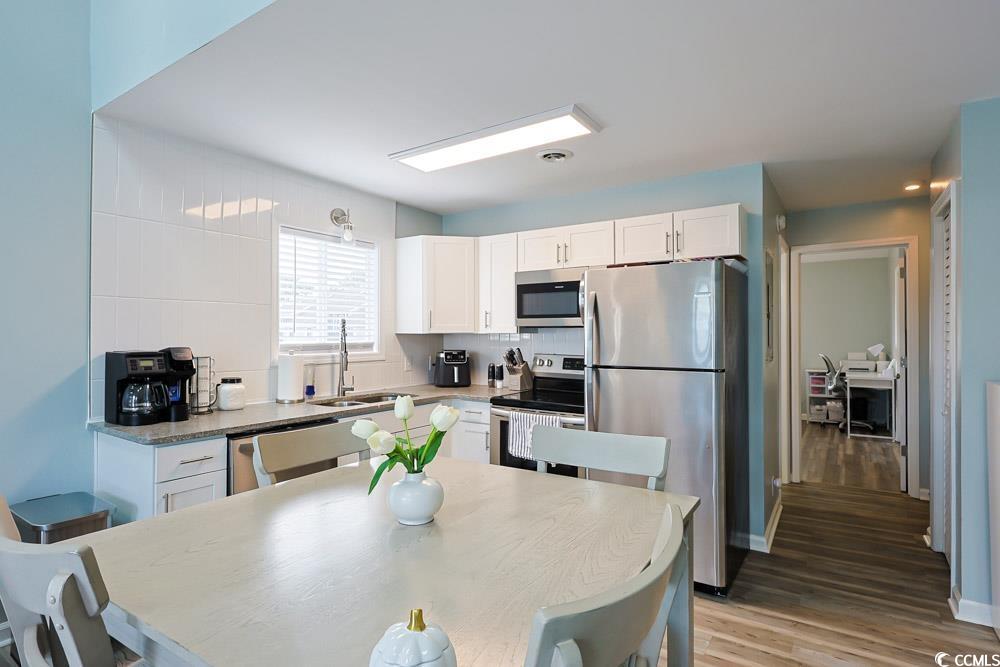 3700 Golf Colony Lane, Unit 5B Little River, SC 29566 - Photo 7 of 27 Kitchen with stainless steel appliances, white cabinets, tasteful backsplash, light wood-type flooring, and light stone countertops