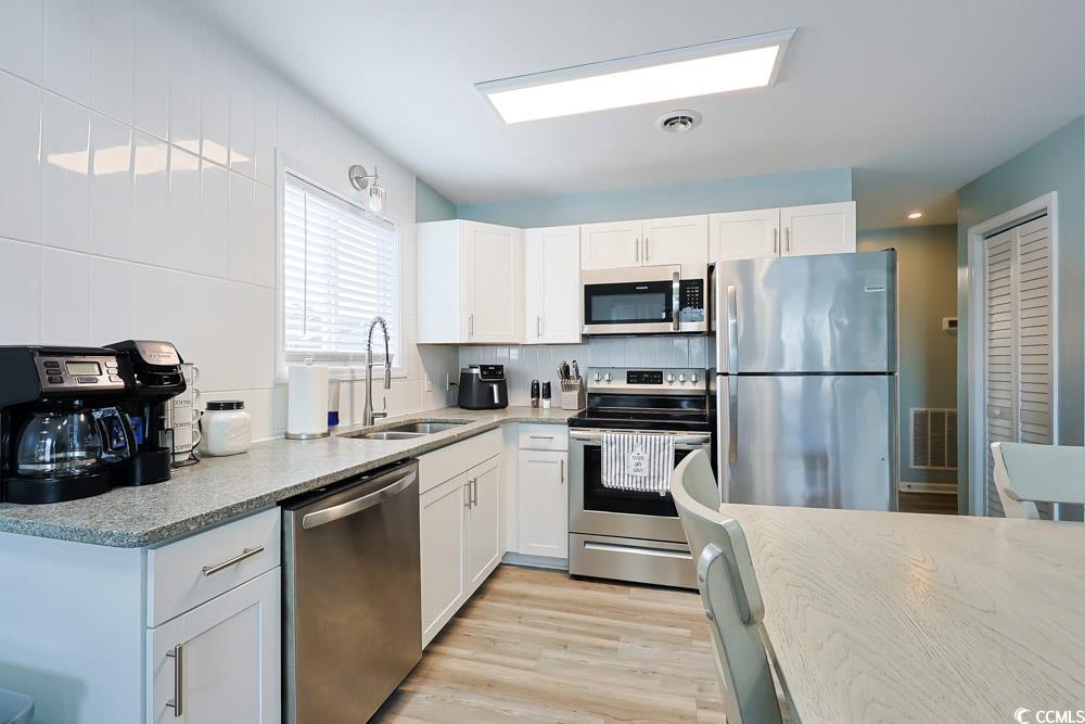 3700 Golf Colony Lane, Unit 5B Little River, SC 29566 - Photo 8 of 27 Kitchen featuring stainless steel appliances, white cabinets, light wood finished floors, and light stone counters