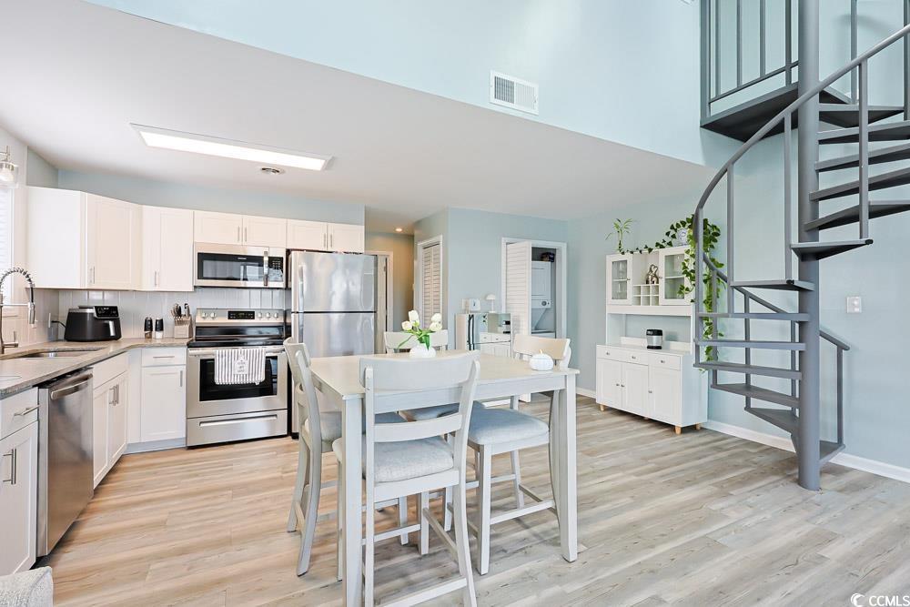 3700 Golf Colony Lane, Unit 5B Little River, SC 29566 - Photo 9 of 27 Kitchen featuring stainless steel appliances, white cabinets, light wood-type flooring, light stone countertops, and glass insert cabinets