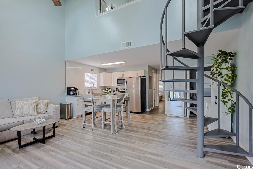 3700 Golf Colony Lane, Unit 5B Little River, SC 29566 - Photo 10 of 27 Dining space featuring stairway, light wood-type flooring, a towering ceiling, and plenty of natural light