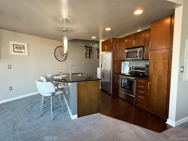 a kitchen with stainless steel appliances kitchen island granite countertop a refrigerator a stove top oven a sink and dishwasher