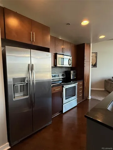 a kitchen with stainless steel appliances granite countertop a refrigerator a stove a sink and a microwave