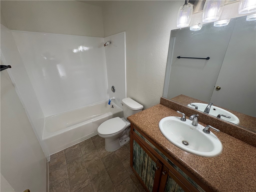 1030 West MacArthur Boulevard, Unit 116 Santa Ana, CA 92707 - Photo 11 of 15 a bathroom with a granite countertop sink a toilet a mirror and shower