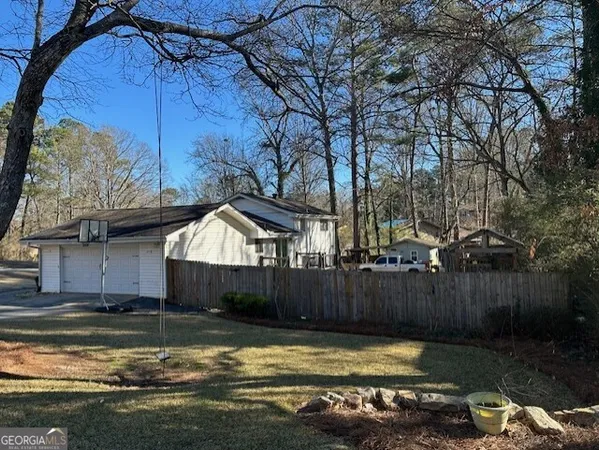 a view of a house with a yard fire pit and a large tree