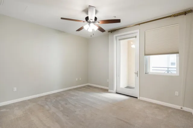 an empty room with a chandelier fan and windows