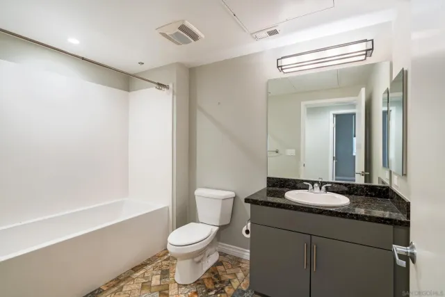 a bathroom with a granite countertop sink a toilet and a mirror
