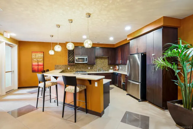 a kitchen with stainless steel appliances granite countertop a refrigerator a sink a stove and chairs
