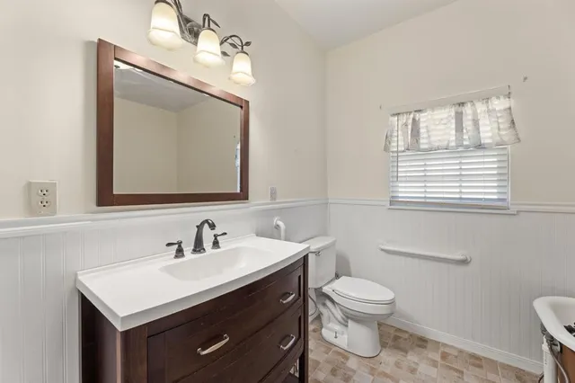 a bathroom with a toilet a sink a mirror and a window