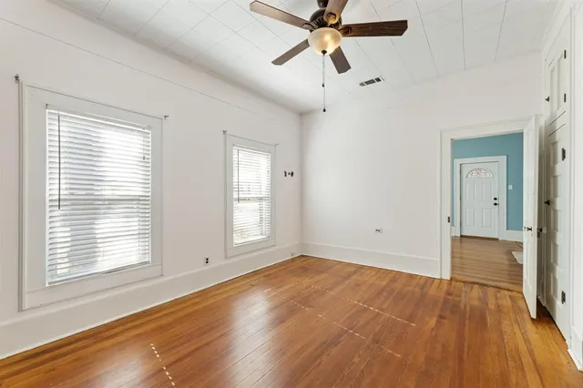 a view of empty room with wooden floor and fan