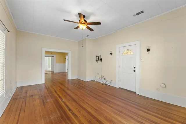 a view of empty room with wooden floor and fan