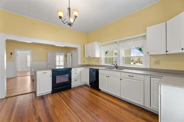 a kitchen with stainless steel appliances granite countertop a sink cabinets and wooden floor