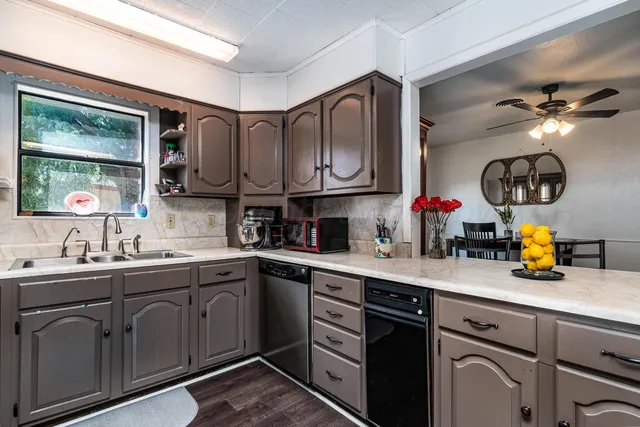 a kitchen with a sink dishwasher a stove and cabinets with wooden floor