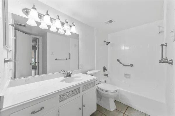 a bathroom with a toilet a sink a tub and a mirror