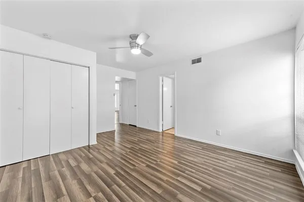 an empty room with wooden floor and windows