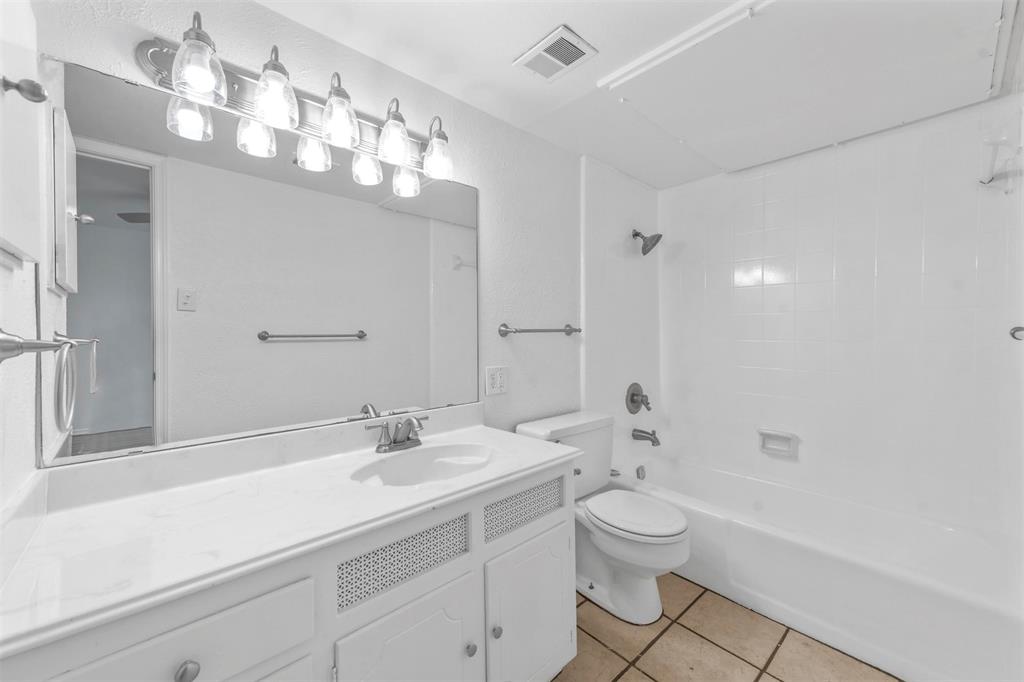 4002 Ridglea Country Club Drive Fort Worth, TX 76126 - Photo 25 of 36 a bathroom with a toilet a sink a mirror and a shower