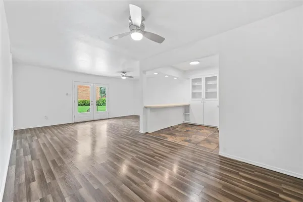 a view of an empty room with a window and wooden floor