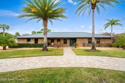 a view of a swimming pool with a yard and palm trees