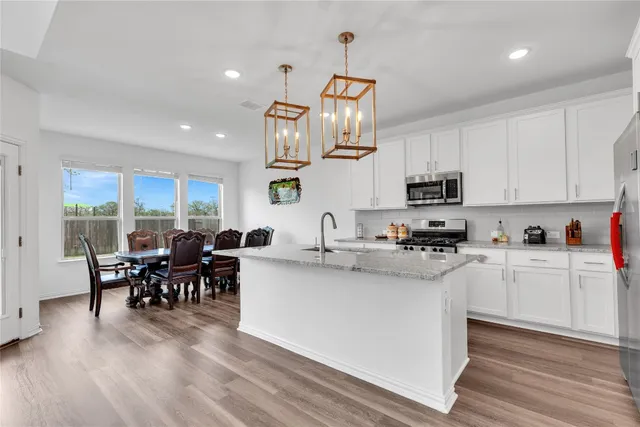 a kitchen with stainless steel appliances granite countertop a sink a stove and a wooden floors